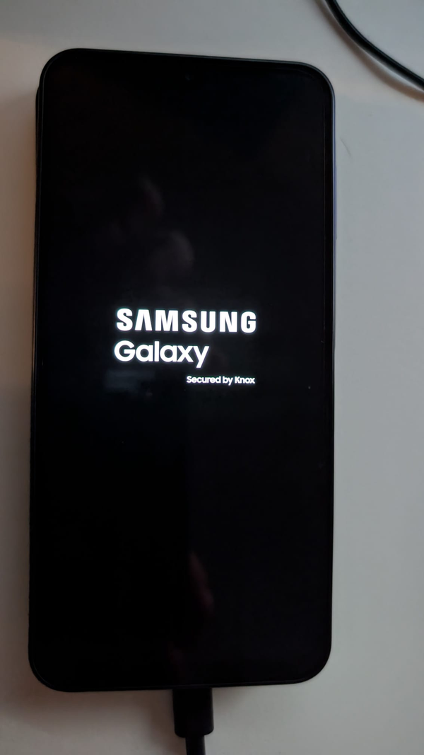 The Samsung Galaxy A17 on its 'SAMSUNG Galaxy / Secured by Knox' boot splash, USB cable attached